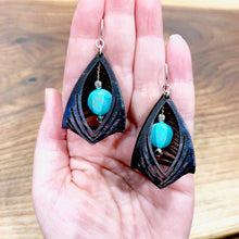 Load image into Gallery viewer, black leather cage earrings with howlite stone in hand
