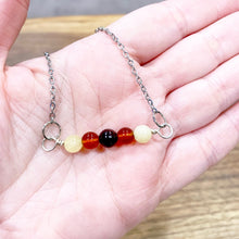 Load image into Gallery viewer, Garnet, carnelian and yellow jade pendant in hand
